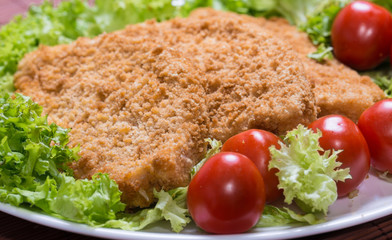 Fried battered chicken breast fillet  with lettuce on the plate