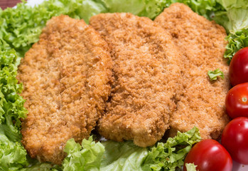 Fried battered chicken breast fillet  with lettuce on the plate