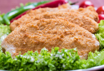 Fried battered chicken breast fillet  with lettuce on the plate