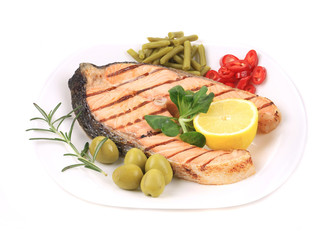 White plate of salmon steak with vegetables.