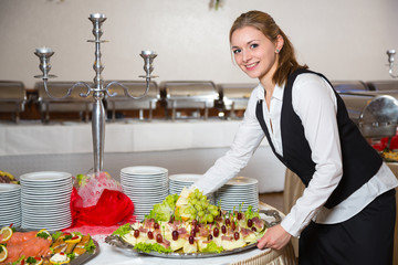 Catering service employee or waitress preparing a buffet