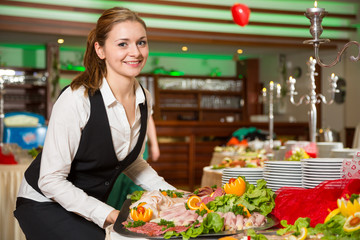 Catering service employee preparing a buffet