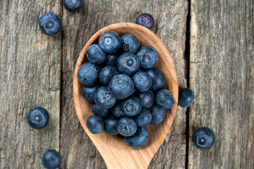 fresh blueberries in a wooden spoon over wooden table