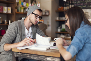Focus college students preparing for exams at cafe