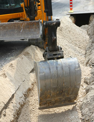 bucket of a bulldozer during the digging in the road in the city