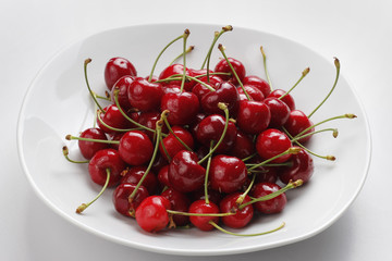 Cerezas rojas en un plato blanco