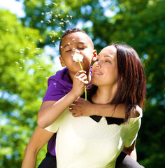 Happy single mother with son blowing dandelion