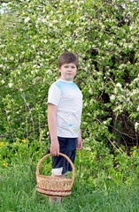 Fototapeta premium Boy with a wicker basket in the spring garden