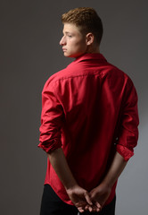 Obraz premium Beautiful young man wearing a red shirt posing with his back
