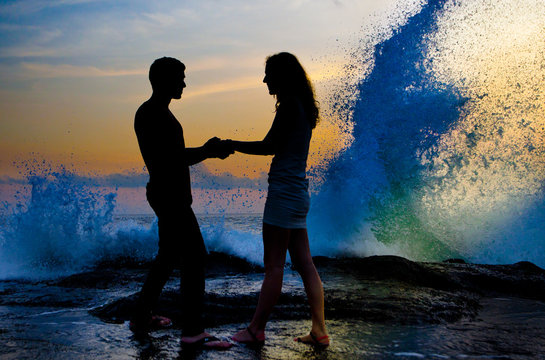 young couple standing and holding in hand on the shore