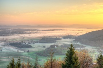 Sunrise above fields covered with morning mists