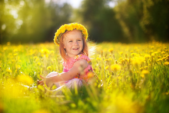 Image of happy child on dandelions field, cheerful little girl r