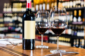 Bottle of red wine and two glasses in wine shop