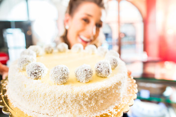 Bäckerin präsentiert Torte in Patisserie