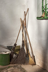The brooms leaning against the wall