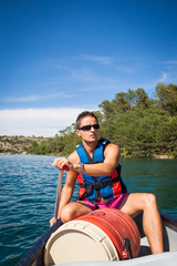 Handsome young man on a canoe on a lake, paddling