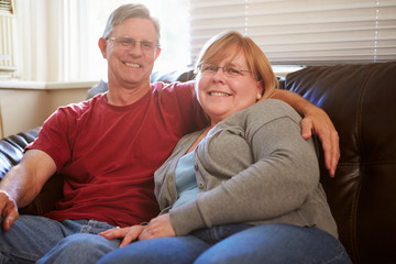Portrait Of Mature Couple Sitting On Sofa At Home