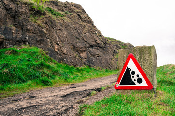 Red warning sign for falling rocks on a hill path in Edinburgh