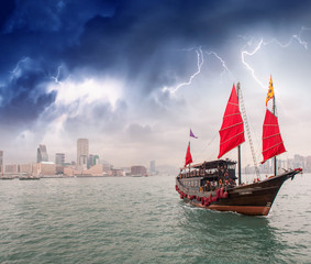 Naklejka premium Sailing ship crossing the sea near a city during a storm