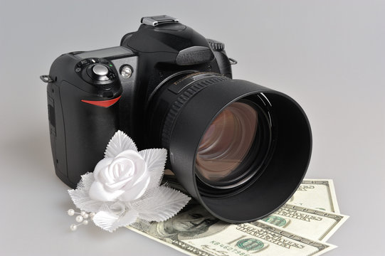 Photo camera, wedding boutonniere with money on gray