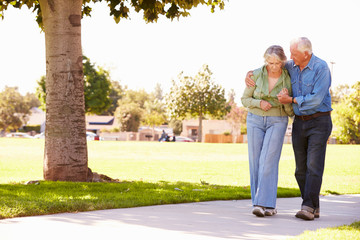 Obraz premium Senior Man Helping Wife As They Walk In Park Together