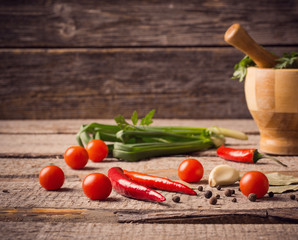 Mortar and pestle with pepper and spices on wooden table
