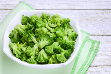 Cooked broccoli in bowl on wooden background