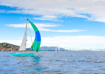 Naklejka premium Sailing boat with a green blue spinnaker out of Poros in Greece