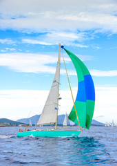 Naklejka premium Sailing boat with a green blue spinnaker out of Poros in Greece