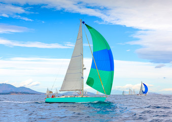 Sailing boat with a green blue spinnaker out of Poros in Greece - 65267790