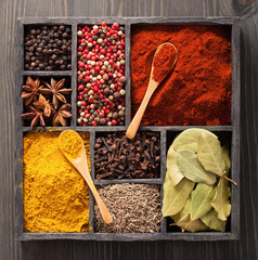 spices in box pink and black pepper, paprika powder, curry, bay