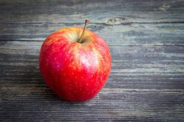 Old red apple on wooden table