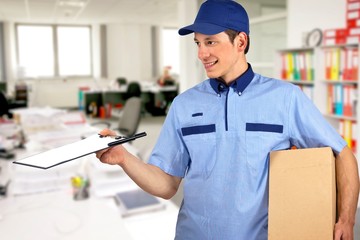 Smiling delivery man, holding clip board and carton box