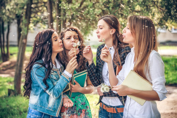 Group of College Girls Blowing Dandelion Seeds