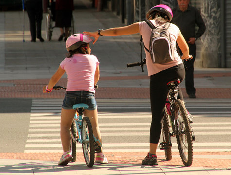 Fototapeta Madre e hija en bicicleta esperando a cruzar la calle