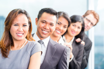 Asian business people standing in row in office