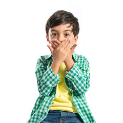 Kid covering his mouth over white background
