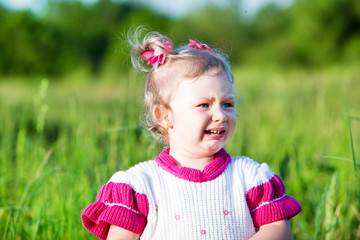 Adorable little child girl  cry on grass on meadow.