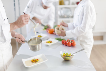 Obraz na płótnie Canvas anonymous hands preparing food in professional kitchen