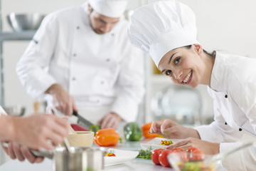  female chef preparing a dish in a professional kitchen - obrazy, fototapety, plakaty