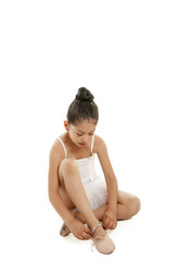 Obraz premium pretty young ballerina student tying up her dance shoes on white