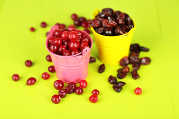 Fresh and dry cranberry in pails on wooden table close-up