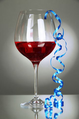 Glass of red wine and streamer after party on gray background