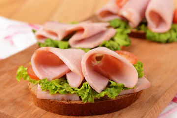 Delicious sandwiches with lettuce and ham on table close-up