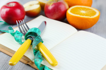 Cutlery tied with measuring tape and book with fruits