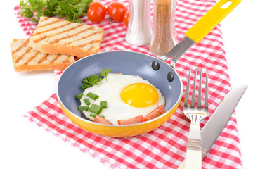 Scrambled eggs and bacon on frying pan on table close-up