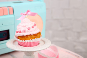 Tasty cup cake with cream on wooden chair