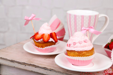 Tasty cup cakes with cream on wooden table