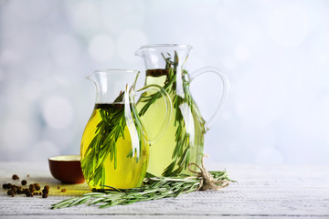 Essential Oil with rosemary in glass jug, on light background