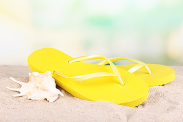 Fototapeta na wymiar Bright flip-flops on sand, on nature background
